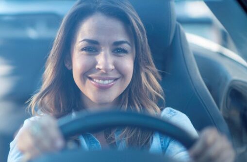 Happy woman driving a car and smiling